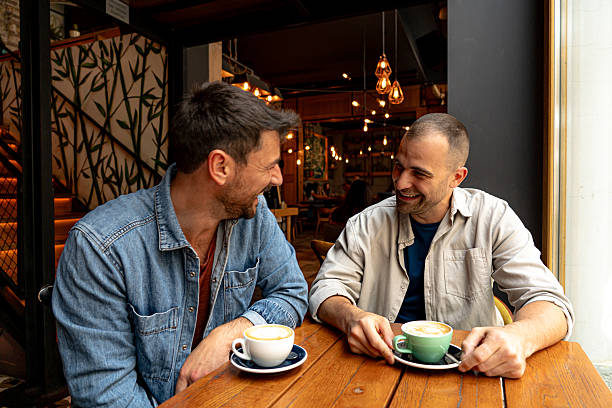 istock Two cheerful men enjoying coffee and conversation at a cafe 2214340919