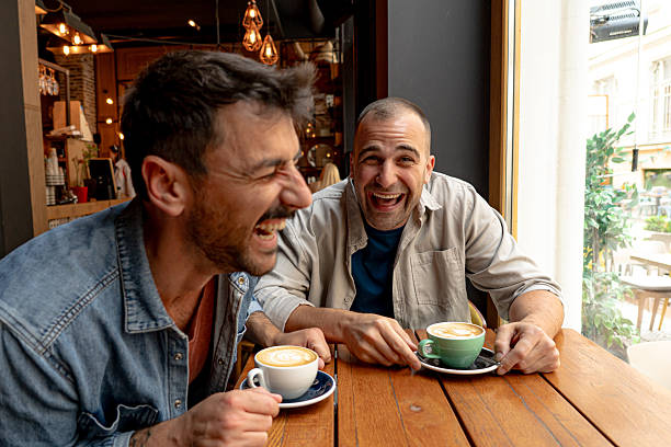 istock Two cheerful men laughing and drinking cappuccino in a cafe 2214340926