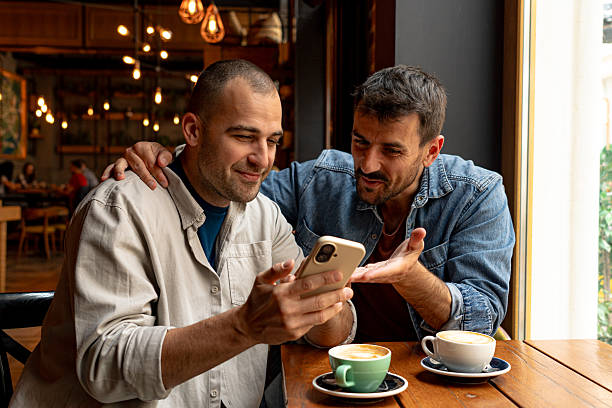 istock Two men looking at smartphone and drinking coffee in cafe 2214340959