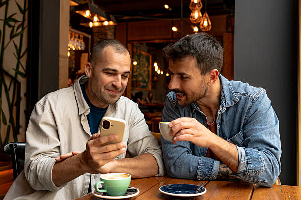 istock Two men enjoying coffee and looking at smartphone in cafe 2214341043