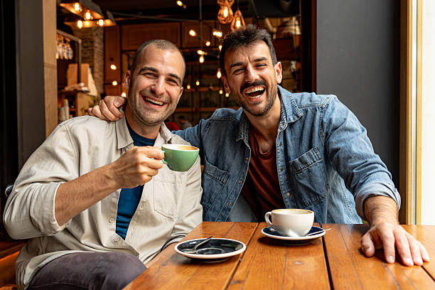 istock Two cheerful men laughing and drinking coffee at a cafe 2214341079