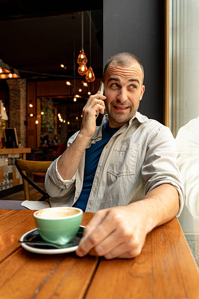 istock Man talking on smartphone and drinking cappuccino in cafe 2214341891