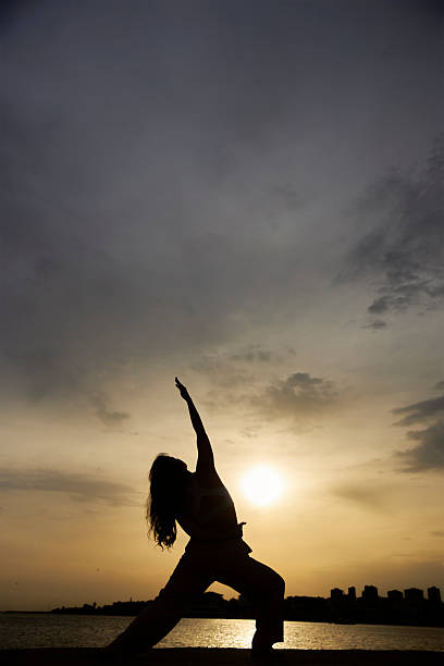 silhouette of a woman at sunset yoga cloudy sky