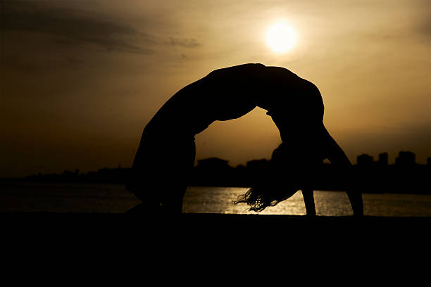 silhouette of a woman at sunset yoga cloudy sky