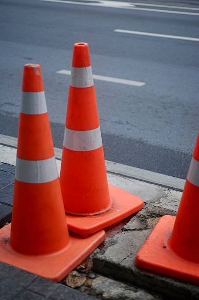 istock Orange traffic cone placed on asphalt with a blurred urban background 2214345880