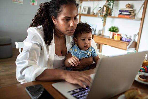 istock Young mother and son having breakfast together while the mother is working on her laptop 2214346685