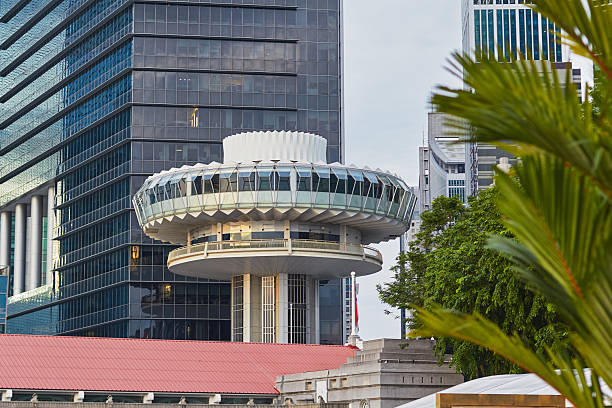 A unique architectural observation deck stands out amidst tall buildings, framed by greenery as the sun sets in the background.