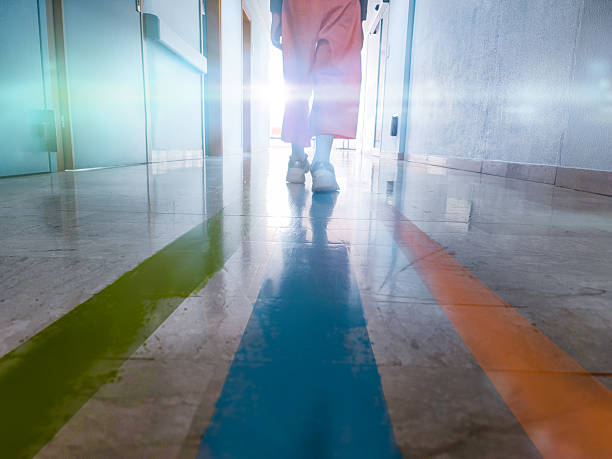 istock Patient Walking Through Hospital Corridor with Colored Guideline Stripes 2214360551