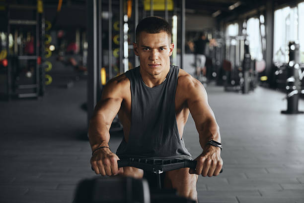 istock Focused handsome man using rowing equipment in modern gym. 2214362181