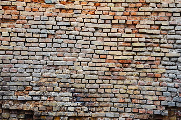 A large wall made of old bricks with dents, cracks and irregularities.