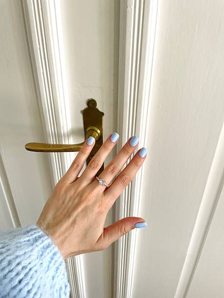 istock Woman's hand with light blue nail polish and a diamond ring 2214370317