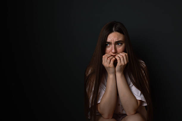 istock Fear of darkness. Scared young woman on black background, space for text 2214372899