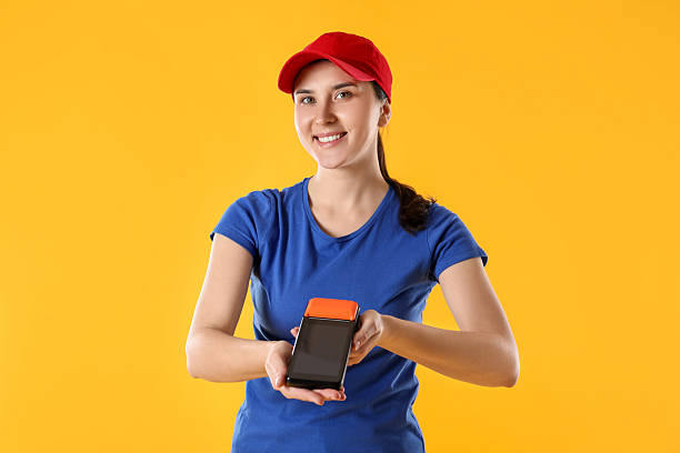 istock Happy courier with payment terminal on yellow background 2214374369