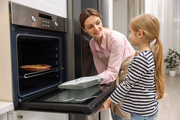 istock Mother and her daughter taking out pie from oven in kitchen 2214375613