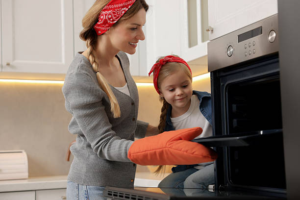 istock Mother and her daughter taking out baking pan from oven in kitchen 2214375627