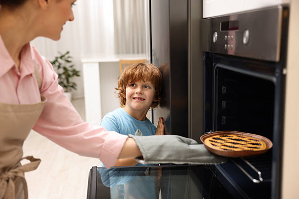 istock Mother and her son taking out pie from oven in kitchen, closeup 2214375654