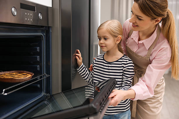 istock Mother and her daughter baking pie in oven indoors 2214375658