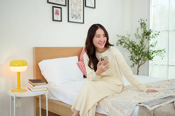 istock Young asian woman using smart phone lying on bed 2214376209