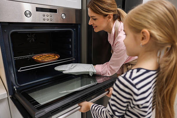 istock Mother and her daughter taking out pie from oven in kitchen 2214376228