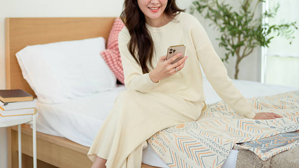istock Young asian woman using smart phone lying on bed 2214376251