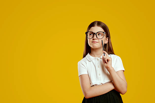 istock Thoughtful girl in glasses pondering creative ideas for a school project on a vibrant background 2214376342