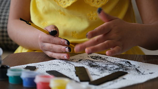 istock Student child paints the model house made by laser cutting with a paintbrush using acrylic paint. Close-up 2214376827