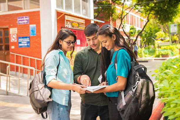istock Three students discussing together on a book at school campus 2214379051