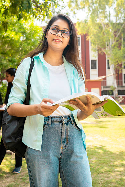 istock Confident happy female student contemplating while reading a book at school campus. 2214379069