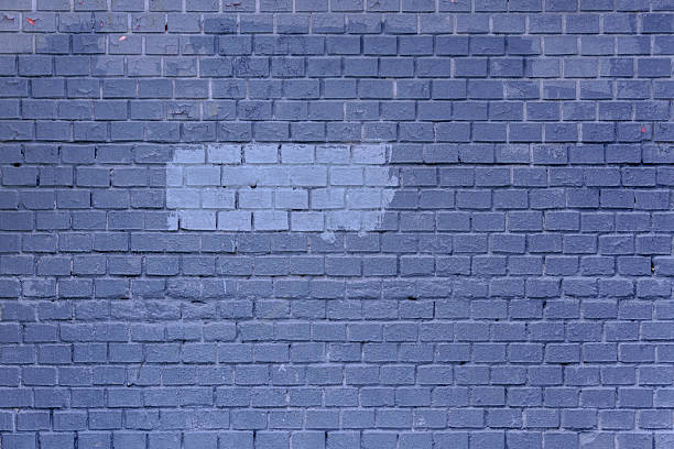 Light gray paint spot on dark gray brick wall. Abstract construction background.