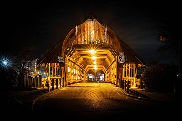 Photo of Bavarian Inn old wooden covered bridge in Frankenmuth Michigan illuminated at night with warm lights and Bavarian charm.