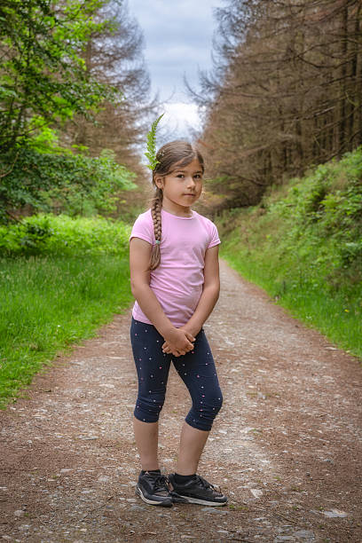istock A Young Girl Standing on a Beautiful Forest Path Adorned with a Floral Crown, Embracing Natures Wonders 2214392379