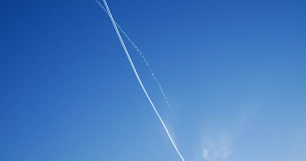 istock Commercial passenger airplanes cruising at high altitude, creating intersecting white contrails against pristine clear blue sky during daytime flight 2214394539