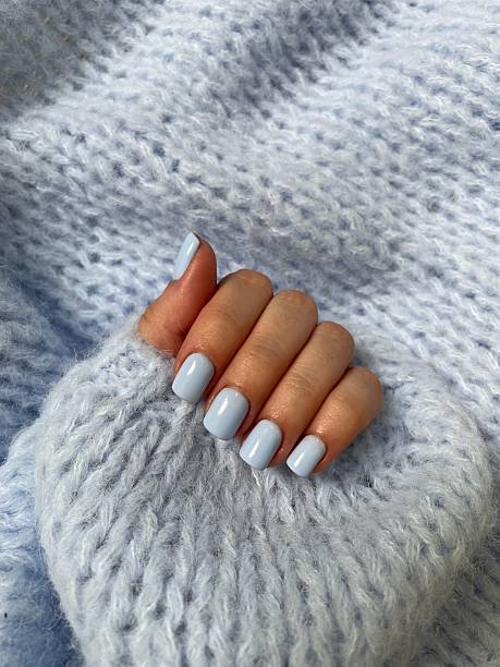 istock Woman's hand with light blue nail polish wearing a soft blue sweater 2214395148