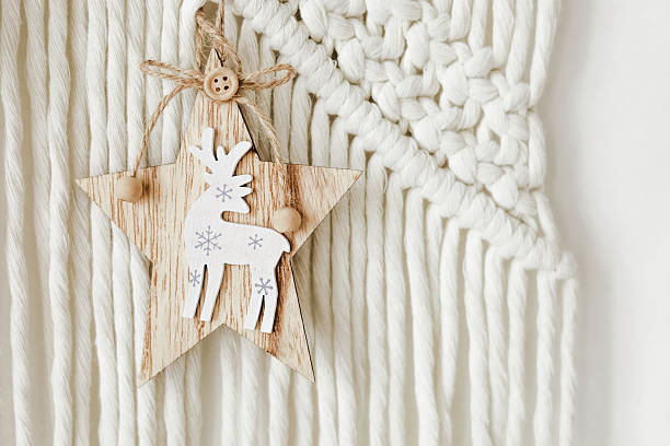 Decorative wooden star with reindeer design hanging on macrame wall decor during holiday season