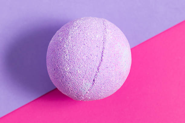 Colorful bath bomb resting on vibrant pink and purple background for relaxing spa experience