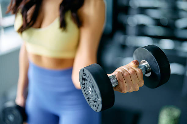 istock Young woman lifting dumbbells during workout in gym 2214401779