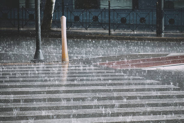 istock Heavy rainfall on urban crosswalk with splashes and reflections in cityscape 2214402803