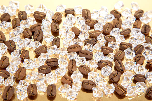 istock Roasted coffee beans scattered with ice cubes on a shiny golden surface, creating a cool yet warm aesthetic. Ideal for iced coffee ads, gourmet visuals, or refreshment concepts 2214405192