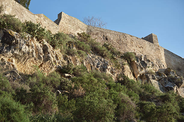 istock Ancient stone wall with lush greenery and rugged rock formations under clear blue sky 2214405508