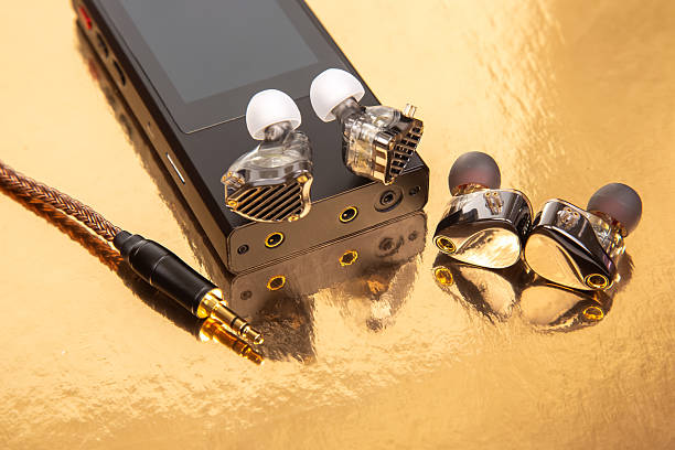 Wired earbuds on a black audio player with a gold backdrop, showcasing a braided cable. Great for technology, sound equipment, and design themes. High-quality image.