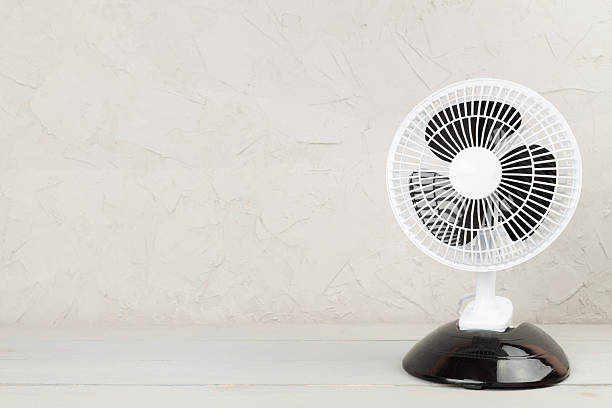 istock Electric fan on wooden background 2214409077