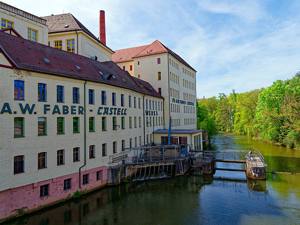 Stein, Germany - April 27, 2025: Old factory facade of the pencil manufacturer Faber-Castell on a sunny day. The building is located on the Rednitz river in Stein. Faber-Castell was founded there in 1761 and is the world's largest manufacturer of colored pencils and pencils.