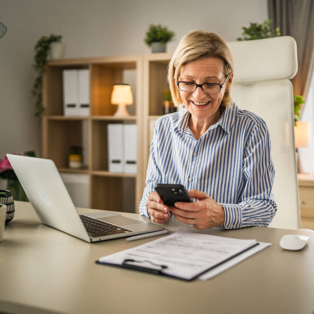 istock Mature woman with eyeglasses use mobile phone at work 2214411510