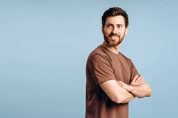 istock Smiling bearded, middle aged man with crossed arms looking away on blue background 2214412729