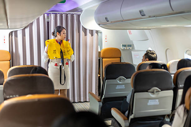 istock Asian flight attendant is demonstrating safety procedure using life jacket before taking off in the airplane for cabin crew and airline business 2214416455