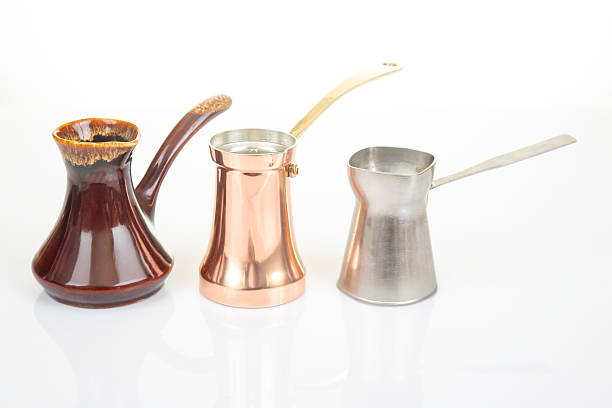 istock Diverse Turkish coffee pots including stainless steel, ornate ceramic, and copper with brass handles, arranged on a white background, suited for traditional coffee brewing and kitchen art shots. 2214418092