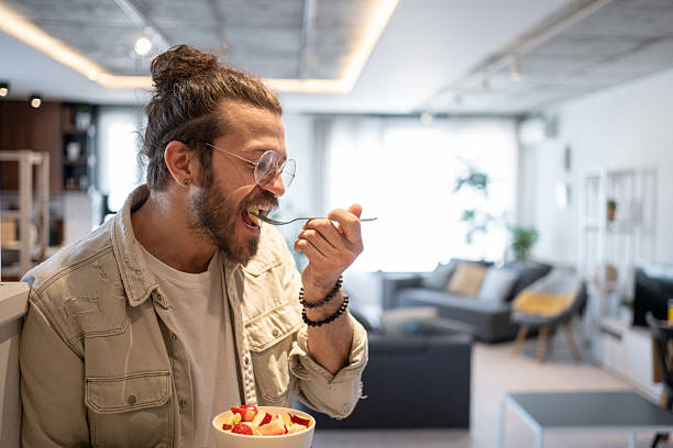 istock Young man enjoying a healthy fruit salad at home 2214424099