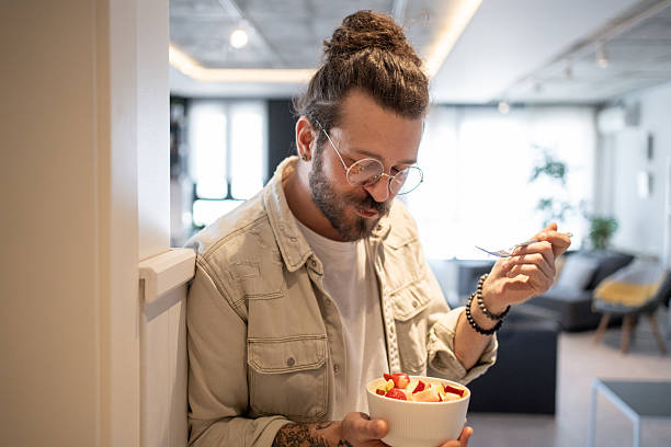istock Young man enjoying a healthy fruit salad at home 2214424102