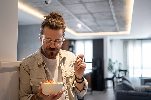 istock Young man enjoying a healthy fruit salad at home 2214424106