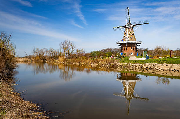 Photo of real Dutch windmill beside water at Windmill Island Gardens in Holland Michigan surrounded by nature and heritage landscape.